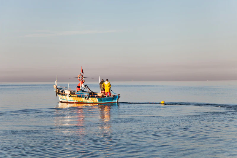 A small fishing boat heading out over calm water at dawn