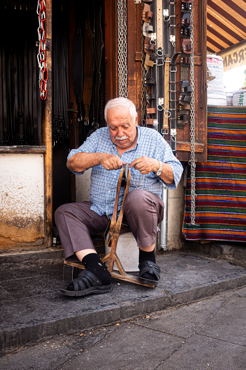 A leatherworker shaping a strap outside his workshop